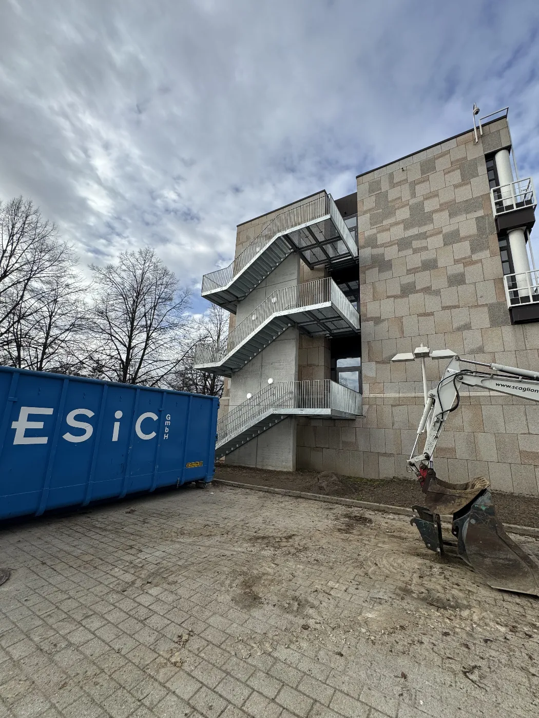Vorgehängte Außentreppe über drei Geschosse, eingespannt zwischen zwei Beton-Wandscheiben