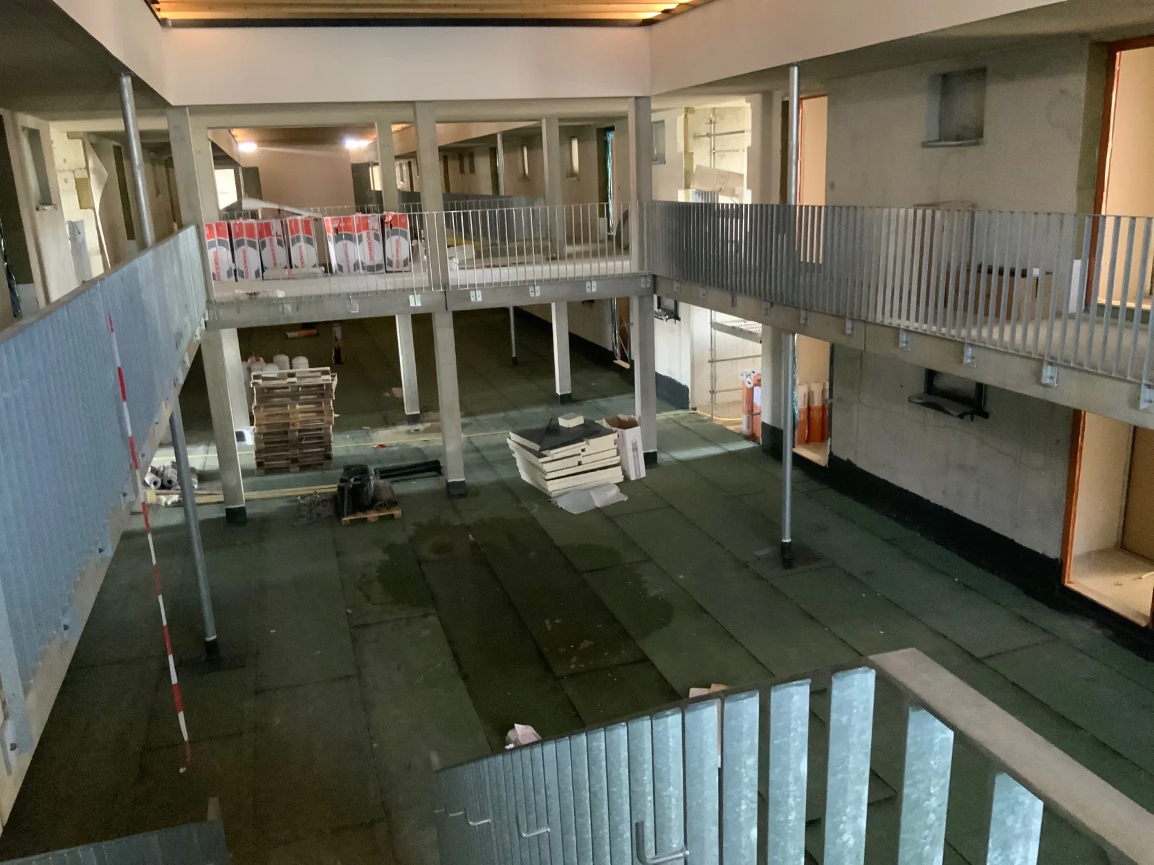 Blick in das Atrium einer Wohnanlage mit Laubengängen und Stahltreppen über drei Ebenen