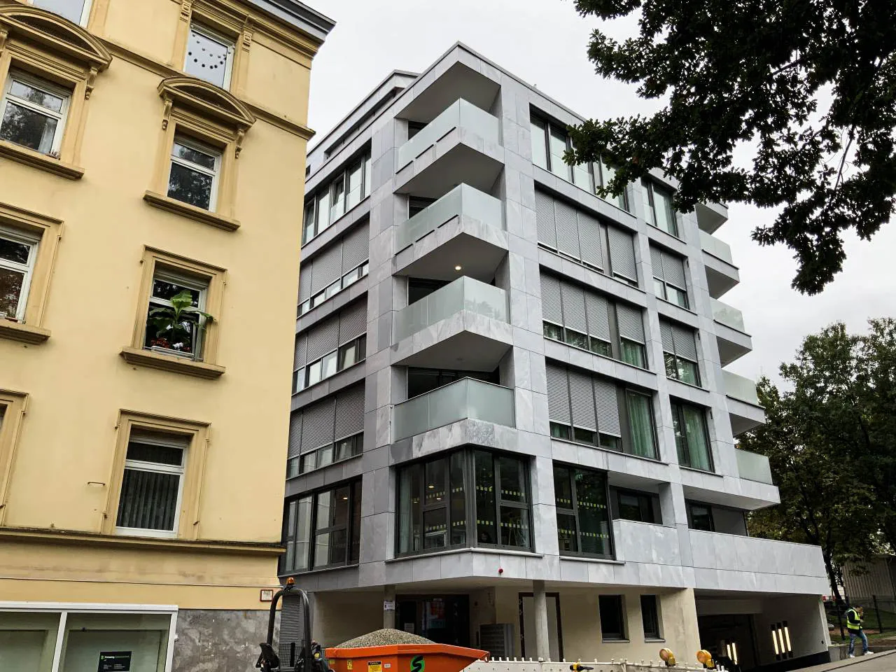 Stadthaus mit heller Marmorfassade und durchlaufendem anthrazitfarbenem Brüstungsprofil über fünf Geschosse