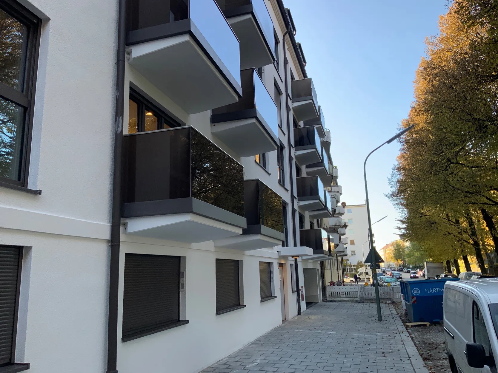 Wohnhaus mit weißer Putzfassade und vier Geschossen anthrazit getönten Rauchglas-Balkonen